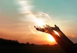 Mains ouvertes vers la lumière du soleil symbolisant la réception d’énergie et l’harmonisation intérieure lors d’un soin énergétique Lahochi.